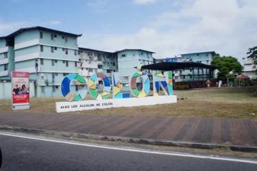 Colon Panama apartment buildings with vibrant Colón sign, sidewalk, and open green space