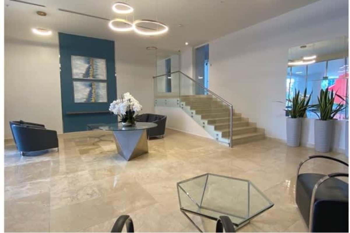 Elegant condominium lobby with floating stairs, marble floors, and art in PH La Loma Tower Panama City