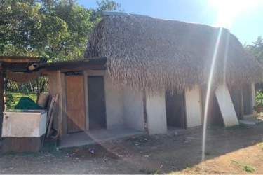 Concrete unfinished building shells with open window frames along dirt driveway Santa Catalina Panama
