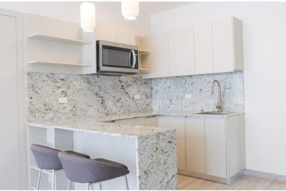 White kitchen with granite counters and pendant lights PH Skypark Costa del Este Panama