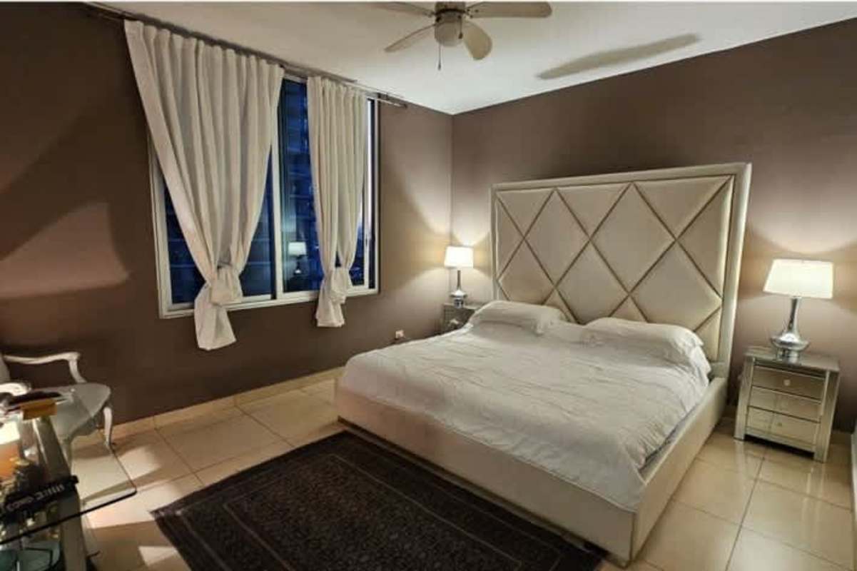 Modern bedroom with upholstered headboard and skyline view at PH Sky Residences Panama City