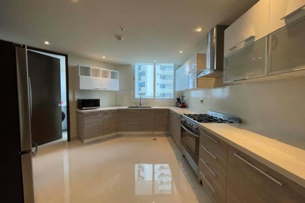 Furnished dining area with modern glass table, chandelier, seating for eight at Costa del Este Panama