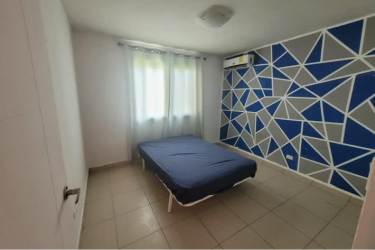 Bedroom with geometric accent wall, tiled floor, navy bedding in Playa Dorada Arraiján Panama rental