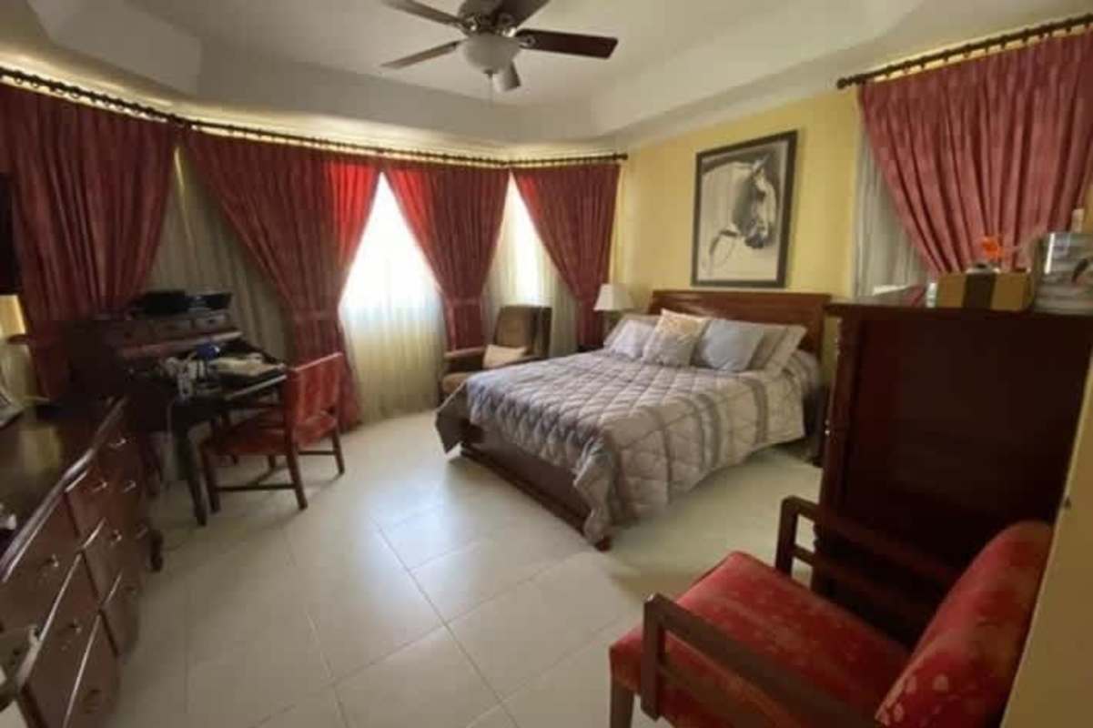 Master bedroom with large windows, wooden furniture, ceiling fan, Dorado Lakes Panama City