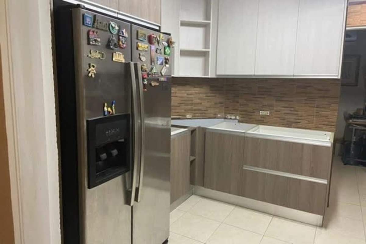 Kitchen with stainless fridge, tile backsplash, upper white cabinets Dorado Lakes Residences