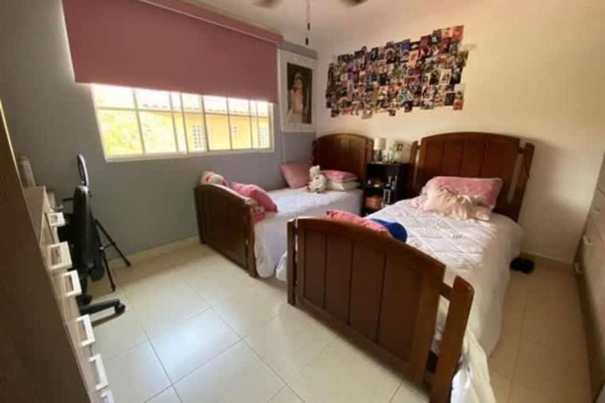 Twin bedroom with pink curtains, tile floor and decor at Dorado Lakes Residences