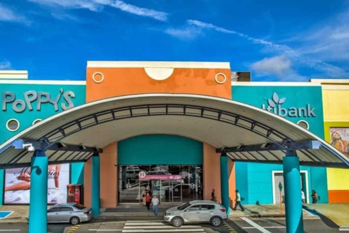 Colorful retail shopping center exterior with palm trees, large signage and parking Albrook Mall Panama City
