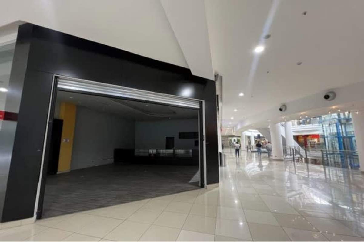 Empty retail space interior with glass front and metal shutter at Los Andes Mall, Panama