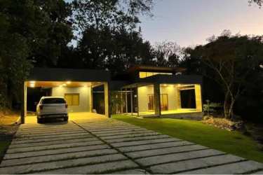Modern house facade with carport and large windows nestled in forest setting in Altos del María Panama