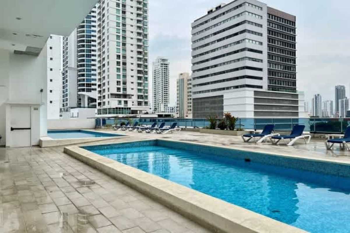 Children's playground on rooftop with trampoline, slide, sports court overlooking Panama skyline Harmony Tower
