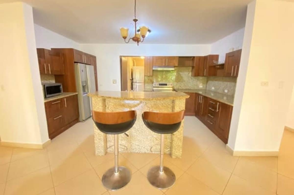 Contemporary kitchen with granite countertops, wood cabinets, stainless appliances in Clayton Panama apartment