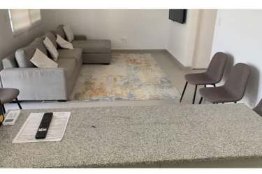 Open concept living area with granite breakfast bar, modern sofa, and tile floors in Nueva Gorgona beach home