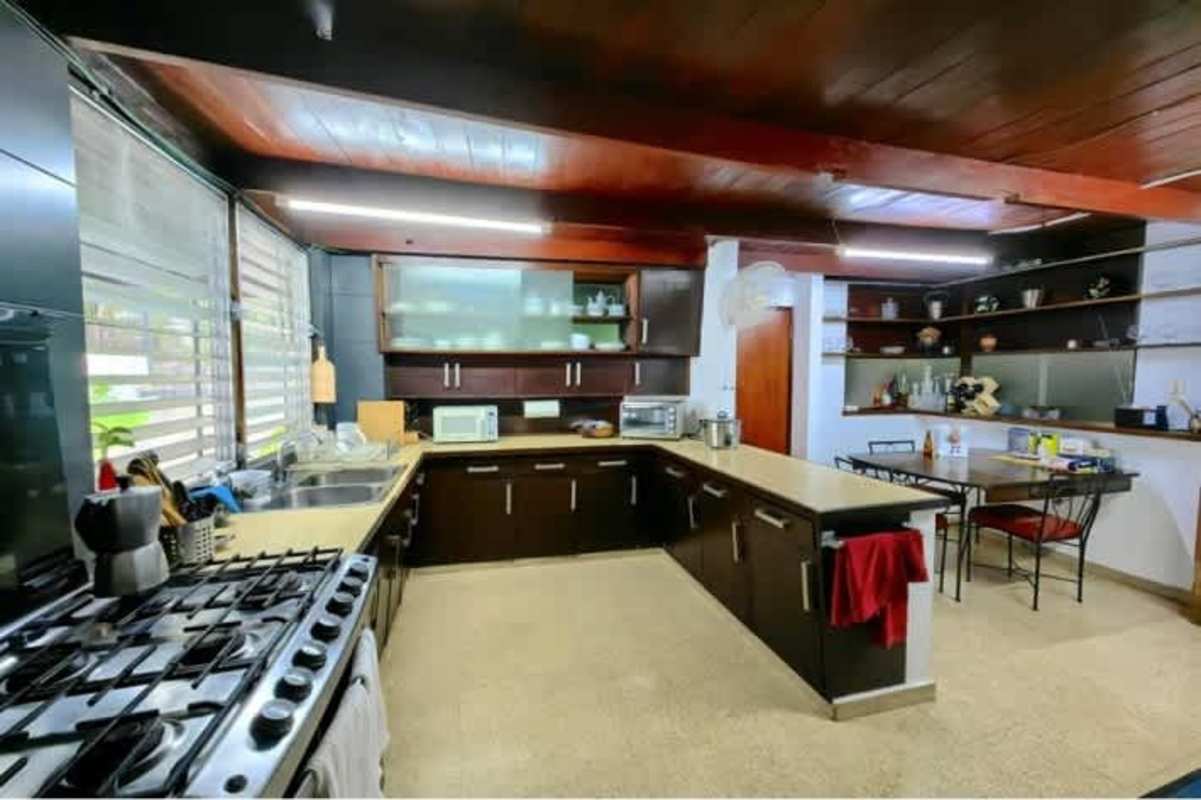 Traditional kitchen with L-shaped counters, wood ceiling, gas stove in Panama City mid-century home