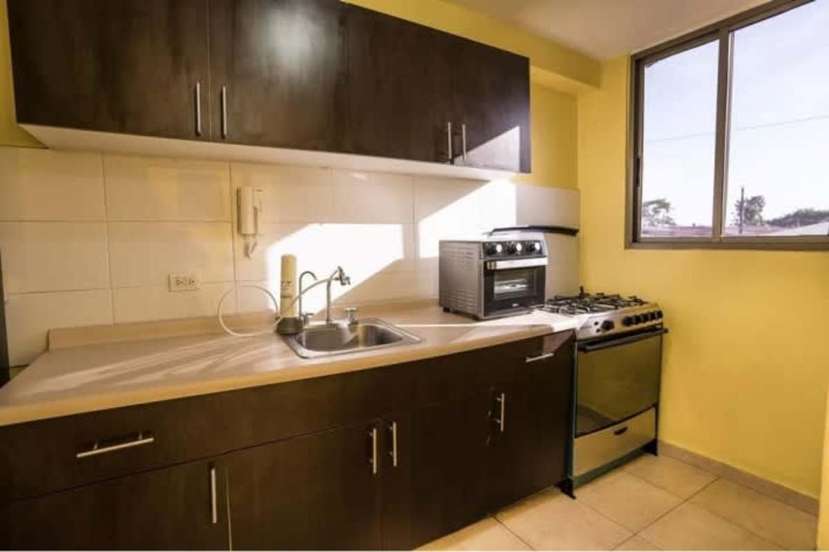 Efficient kitchen with dark cabinets, stove, large window at Chanis Garden Panama