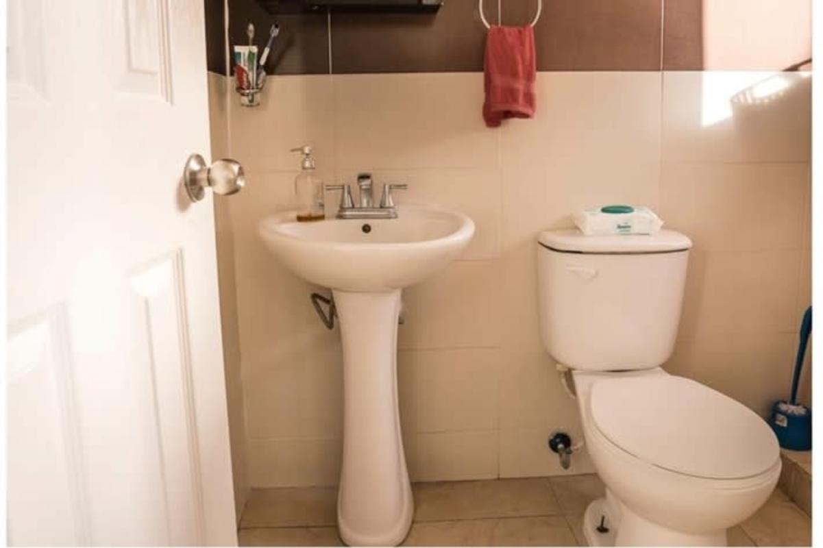 Modern bathroom with pedestal sink, tile walls and toilet in PH Chanis Garden Panama City