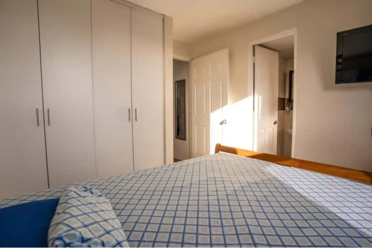 Bedroom featuring built-in closets, window, and air conditioning unit in Chanis Garden Panama