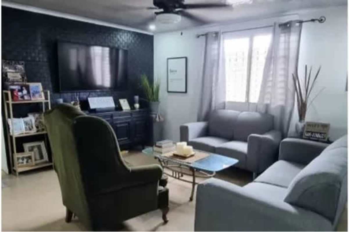 Living room with gray sofas, TV on dark accent wall, glass coffee table in Don Bosco house Panama