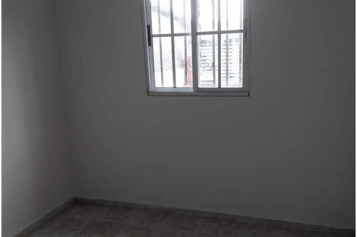 Spacious bedroom with window security bars and tiled floor in affordable house in Tocumen Panama