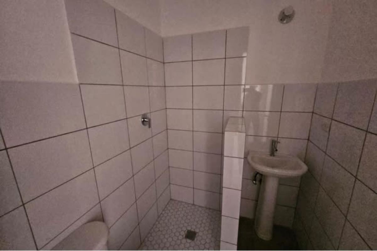 Minimalist bathroom with white tiles walk-in shower restored Casco Viejo apartment Panama City