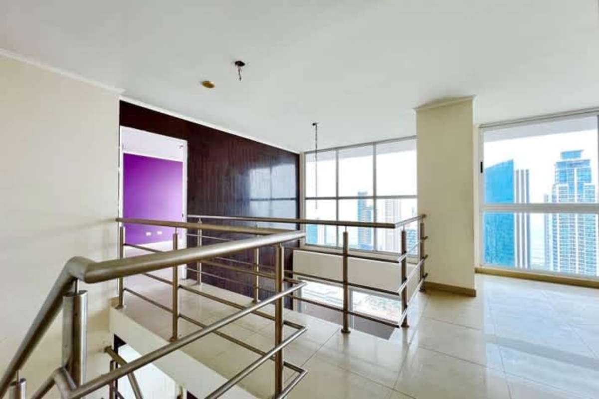 Double-height living room with floor-to-ceiling windows balcony ocean skyline views in PH Sevilla Panama