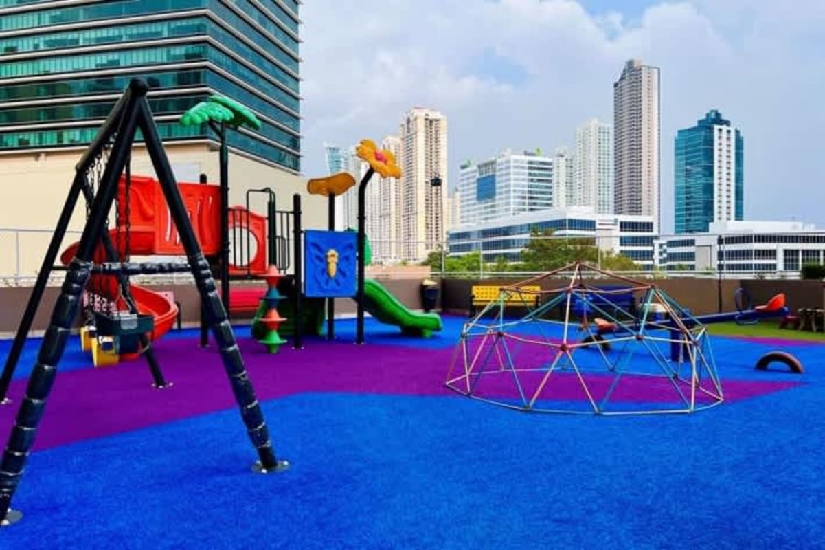 Colorful kids playground rooftop slide swings domes skyline background PH Sevilla Panama