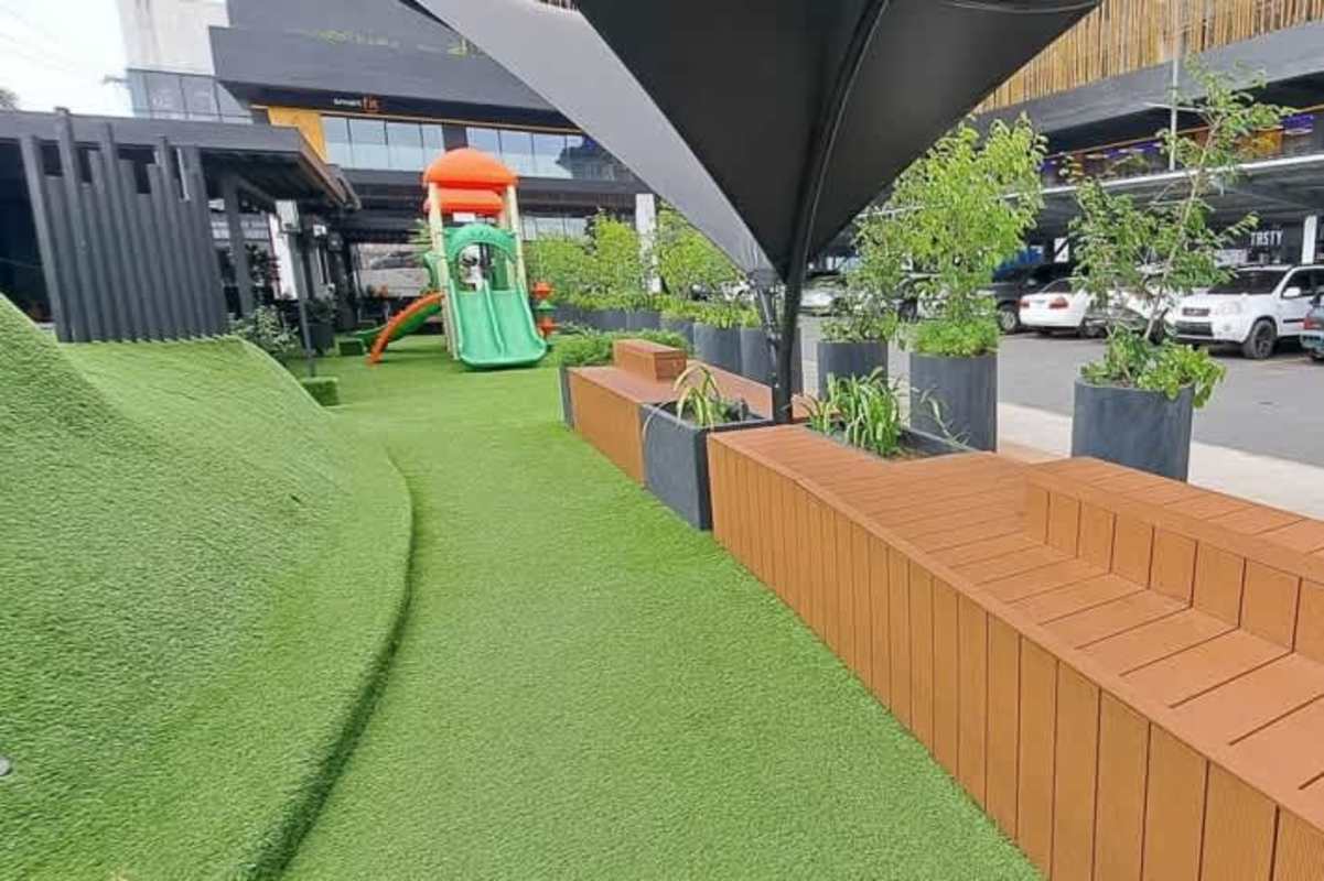 Kids playground area with artificial grass, benches and shaded zones in Greenwood District commercial plaza Panama City