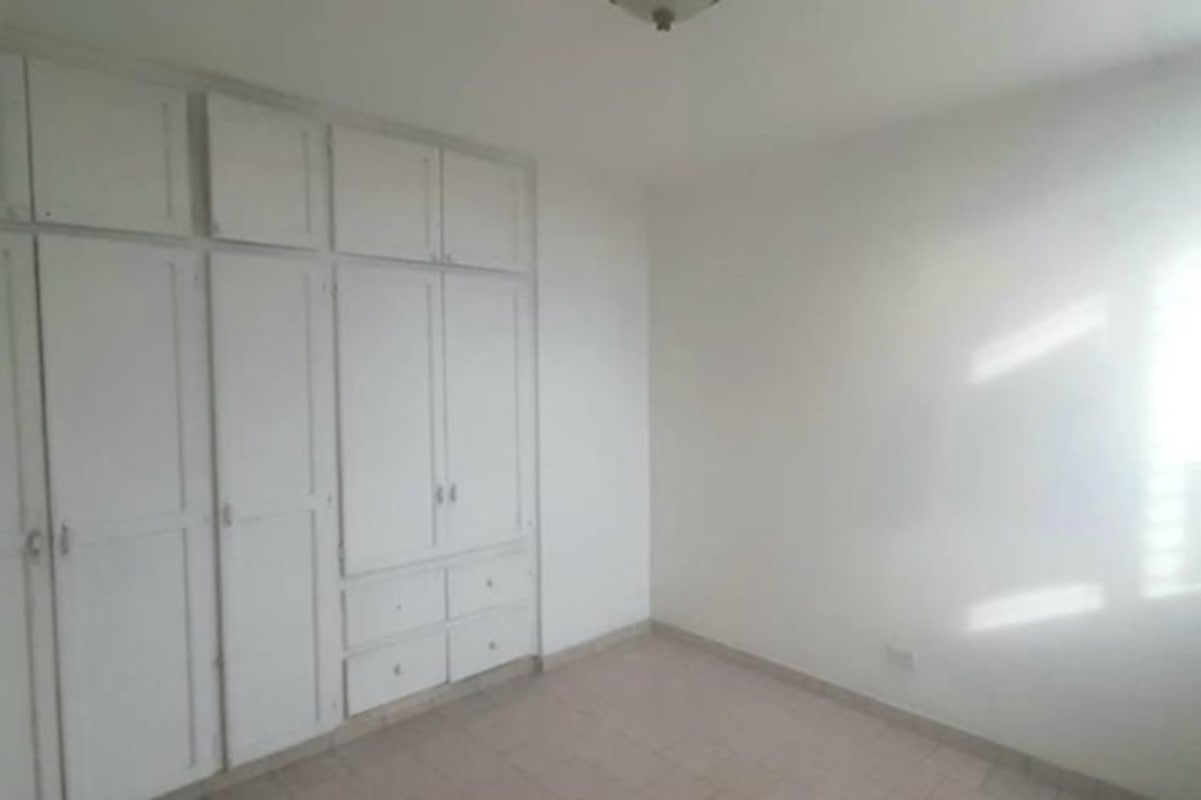 Empty bedroom with white walls, built-in wardrobes and tile floor in PH El Cangrejo Panama City