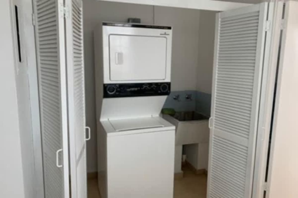 Compact laundry closet with stacked washer dryer behind louvered doors at PH La Alameda Betania Panama
