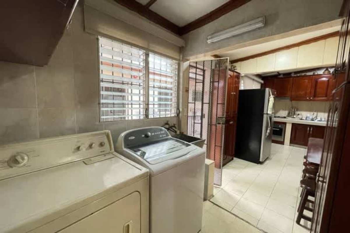 Laundry appliances beside traditional wooden cabinet kitchen in Betania Panama residential
