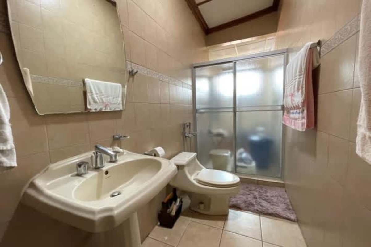 Traditional tiled bathroom with pedestal sink and frosted shower enclosure in Betania residential for sale