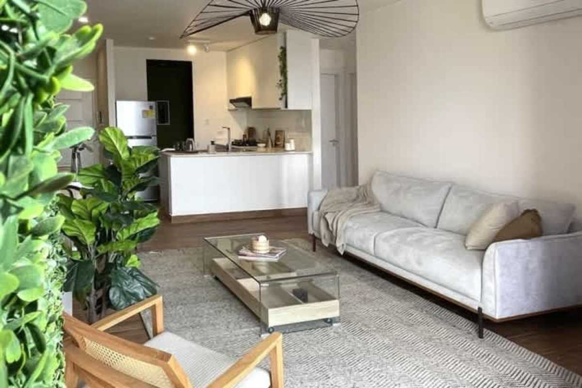 Spacious open living with gray sofa, minimalist décor, and kitchen in PH Sky Swiss El Cangrejo Panama City