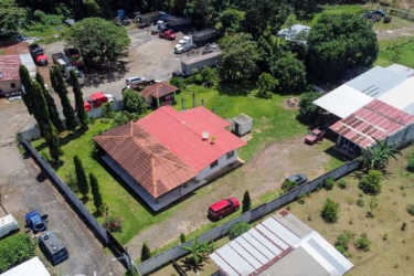 Single-story house with red tiled roof, fenced yard, multiple vehicles, workshop area in La Chorrera Panama