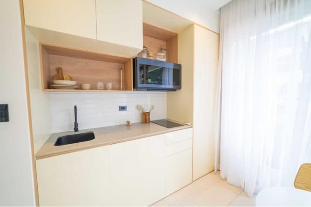Small modern kitchenette with subway tiles, wood cabinets, black fixtures in Bella Vista smart home Panama City
