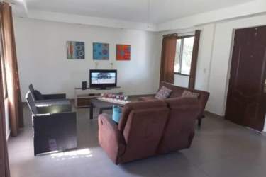 Bright living room with sofas, TV, and art in Club Ecuestre Coronado home