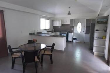 Bright open kitchen with glass dining table and white cabinets in Coronado home