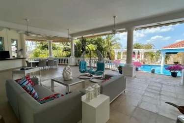 Outdoor living patio with Mediterranean columns, lounge area by private pool in Coronado mansion