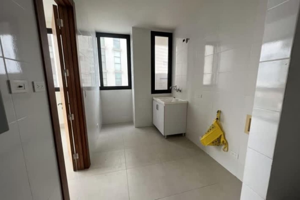 Bright laundry utility room with white tile walls large window at Santa María Panama