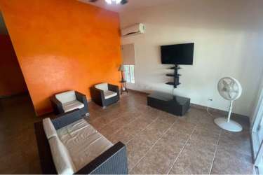 Spacious living room with orange accent wall wicker furniture tile floor PH Villa Brisas de Lajas Coronado Panama