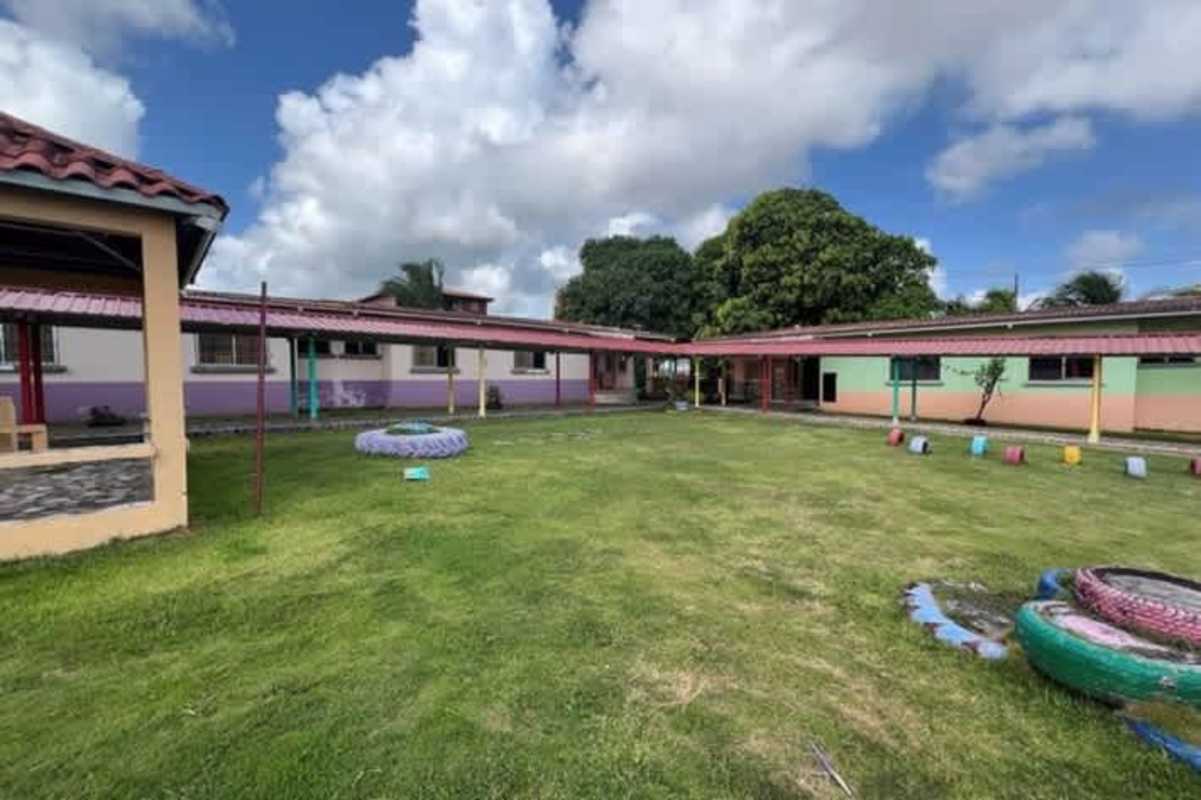 Green lawn with colorful single-story education buildings Colon commercial complex for sale