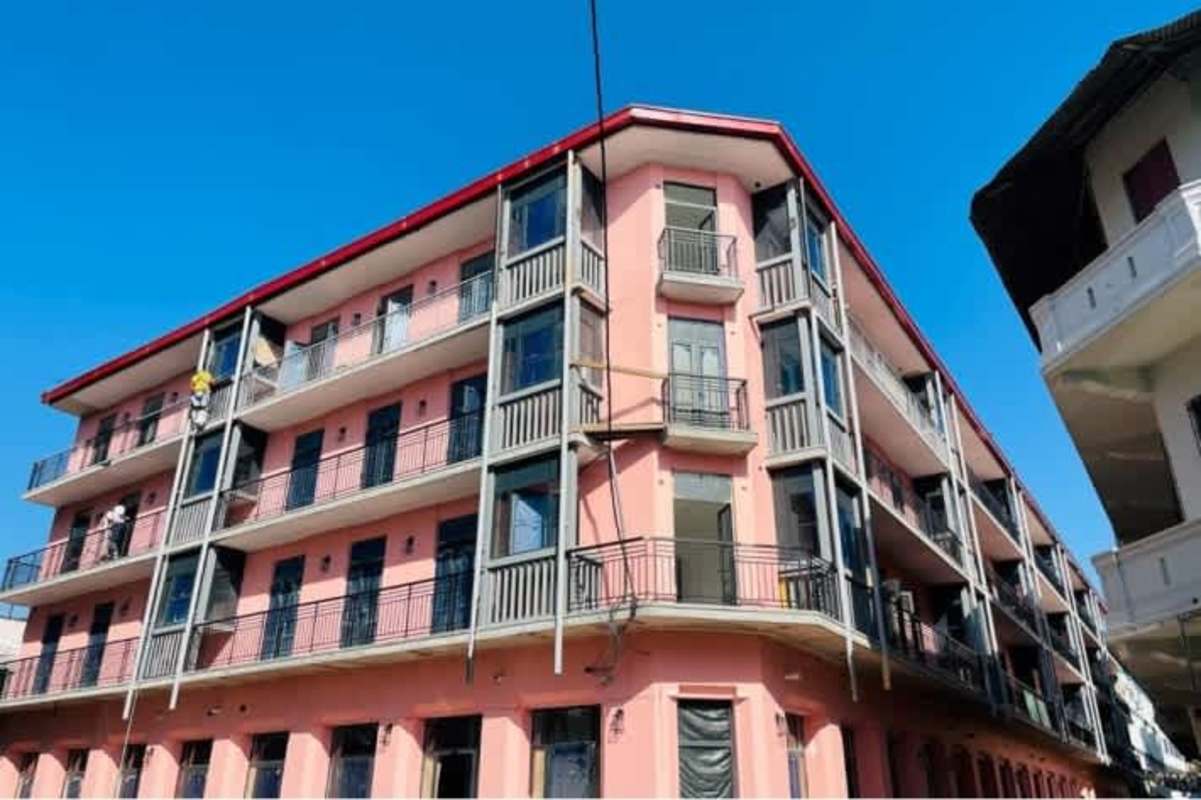 Restored corner pink apartment retail building with balconies and large windows Casco Viejo Panama