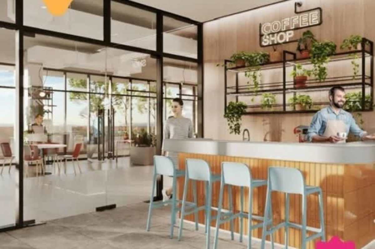 Glass-walled modern café with wood accents, blue stools, indoor plants at PH Altamira Gardens Condado del Rey