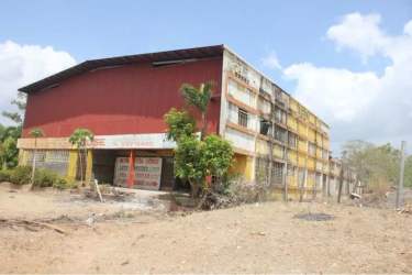 Multi-story industrial building with faded paint beside Pan-American Highway Aguadulce on large dirt lot