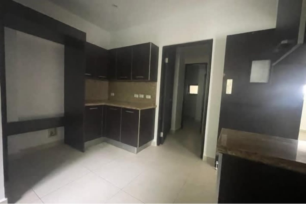 Modern L shaped kitchen with black cabinets and granite backsplash in Panama apartment