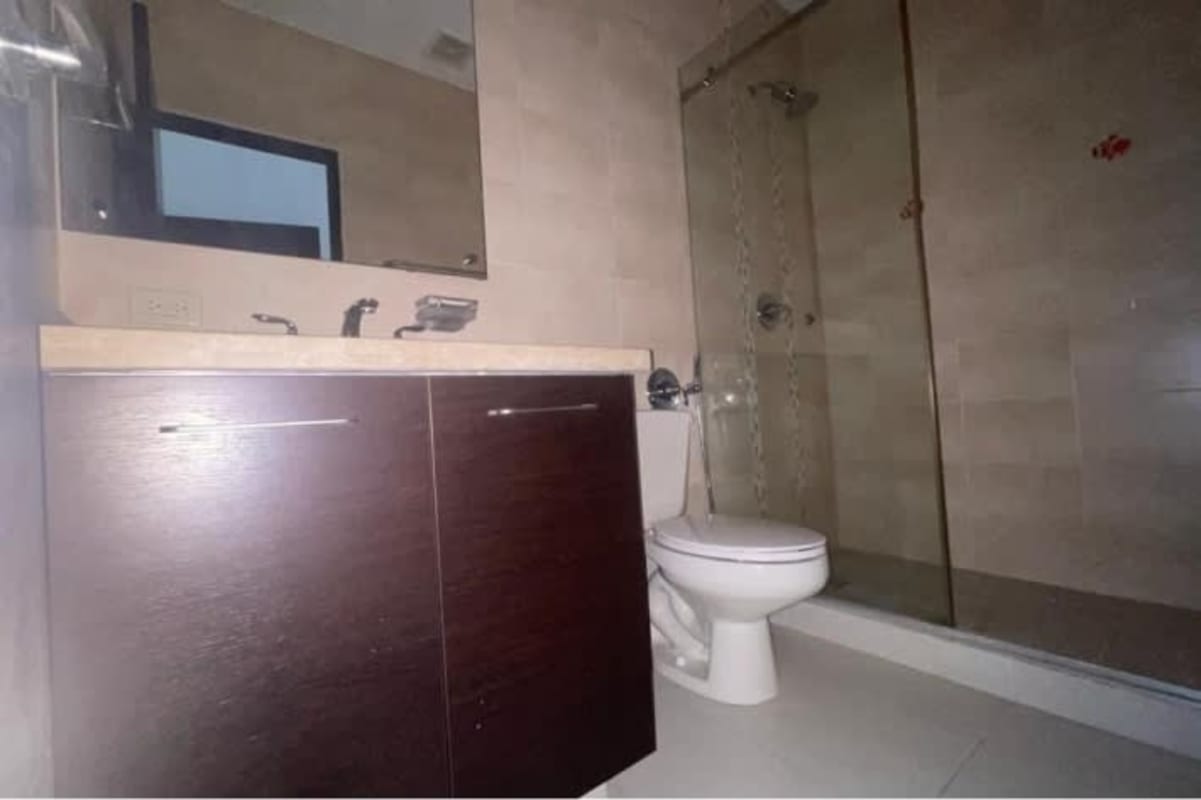 Modern bathroom glass enclosed shower dark wood vanity granite top in Panama City apartment