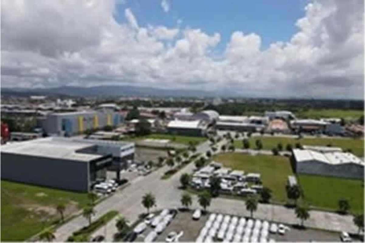 Panoramic aerial of warehouses, landscaped areas, parking, trucks, sky and mountains in Santa María Business District Panama