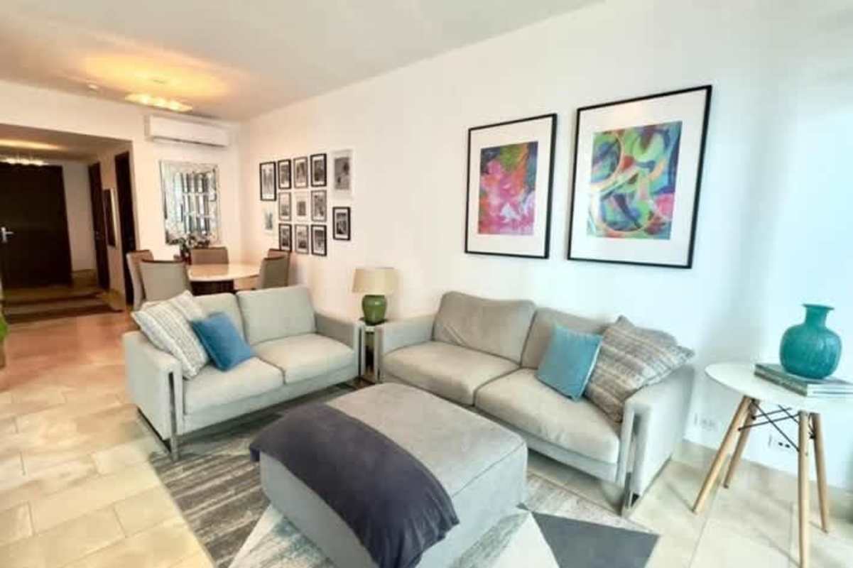 Open living room with floor-to-ceiling windows, modern furniture and city view in Grand Tower Punta Pacifica Panama City