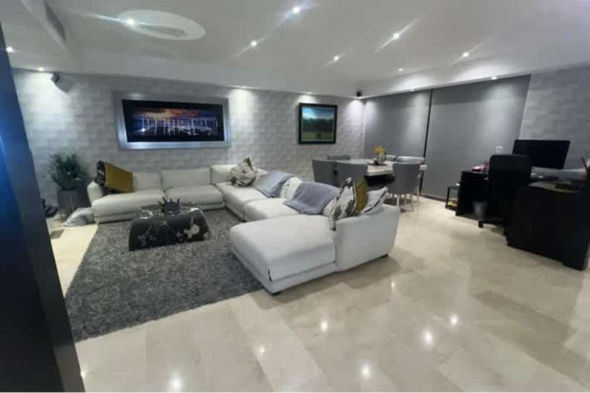 Modern living space featuring sectional sofa, accent wall with shelves, marble floors at PH Miramar Plaza Panama