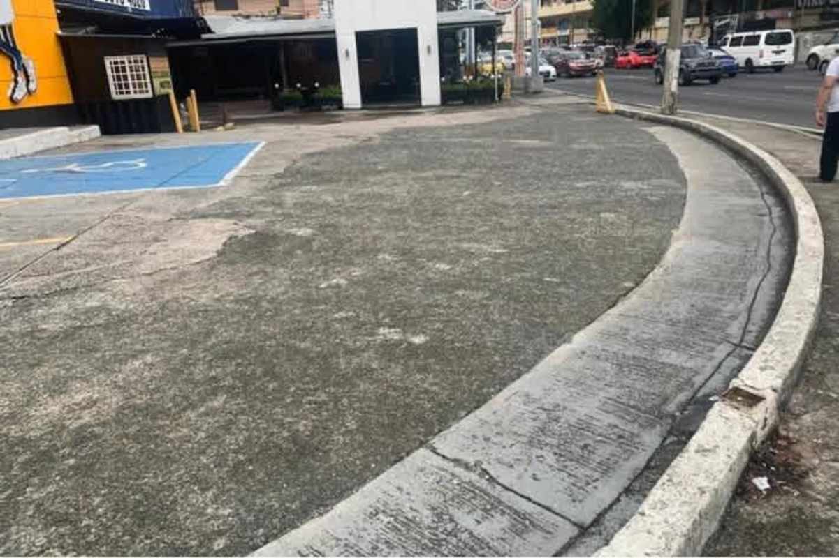 Curved sidewalk and retail parking lot with traffic in Via España Panama