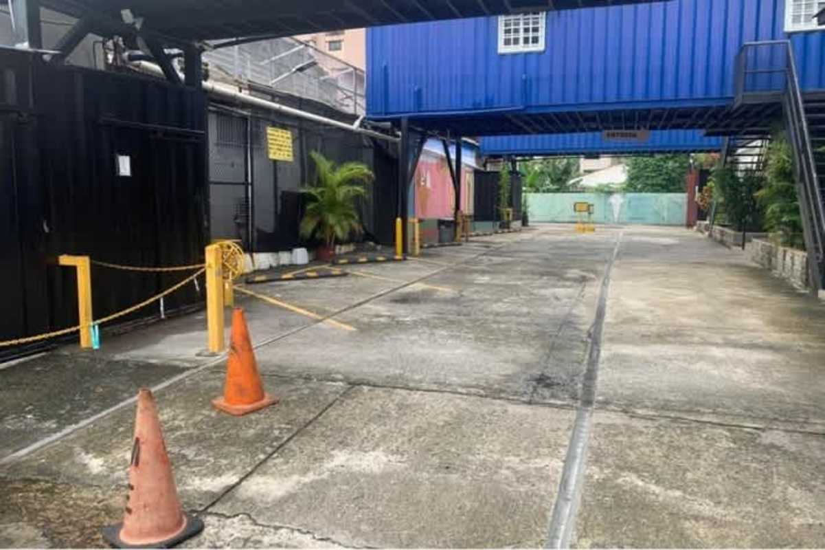 Parking area with shipping container structures, barrier posts, potted plants Via España Panama