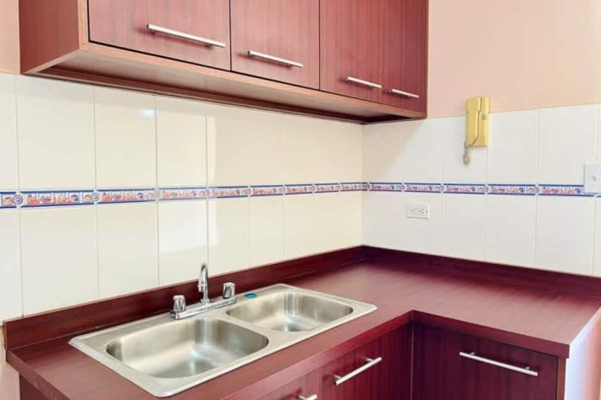 Modern kitchen with granite countertop, arched doorway, cabinetry and tile backsplash Panamá City apartment rental